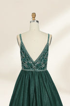 A photograph of a mannequin showcasing a floor-length, sleeveless, dark green evening gown. The gown features a V-neckline embellished with intricate beadwork and a fitted bodice that transitions into a voluminous tulle skirt. The background is plain and off-white, emphasizing the gown's elegant design.9133b.6