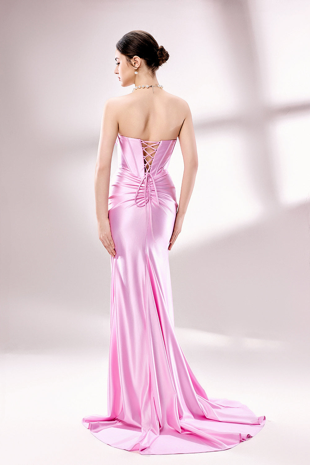 photo of a beautiful woman, elegant evening gown, pink satin, strapless, corset top, high slit, standing pose, long legs, slim figure, fair skin, brunette hair in a bun, large hoop earrings, statement necklace, grey high heels, studio setting, soft lighting, white background, minimalistic, fashion photography, glamour, sophisticated, full body shot, model looking directly at camera.D-138-04