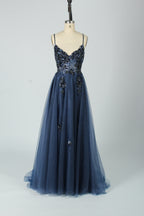 A woman stands against a light background, wearing a blue tulle gown. It features thin straps, a deep V - neckline, intricate floral appliqués with sequins on the bodice, and a high side slit. The voluminous tulle skirt creates a romantic and glamorous look, perfect for formal events like proms or weddings.7