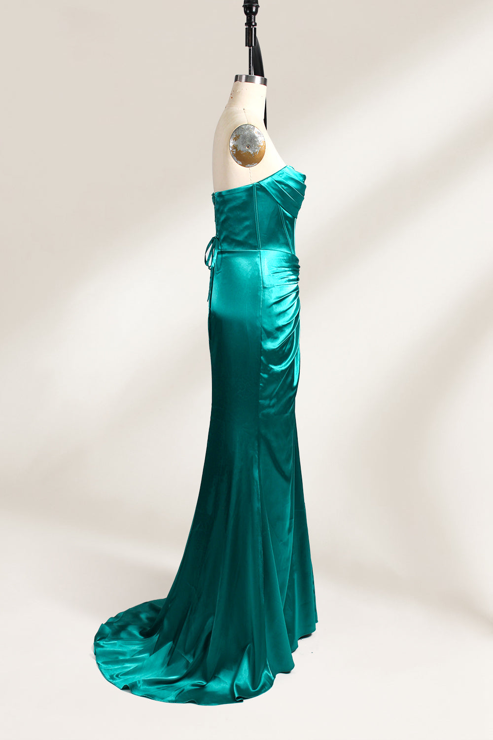 
A mannequin showcases a teal satin strapless gown. It has a ruched bodice, a fitted silhouette, and a flowing, floor - length skirt with a subtle train. The elegant design, featuring gathered details, makes it suitable for formal events like galas or weddings.3