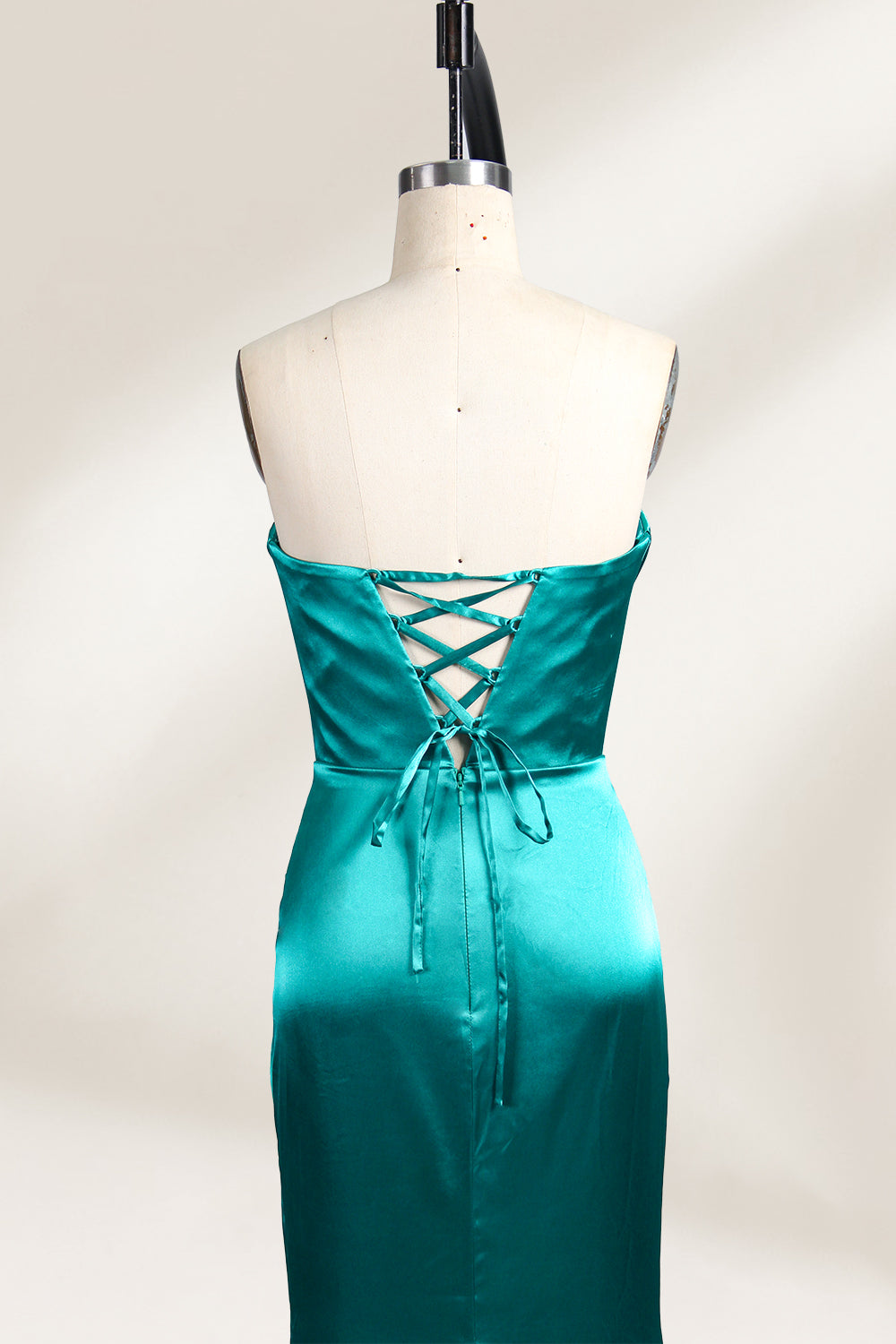 A mannequin showcases a teal satin strapless gown. It has a ruched bodice, a fitted silhouette, and a flowing, floor - length skirt with a subtle train. The elegant design, featuring gathered details, makes it suitable for formal events like galas or weddings.4