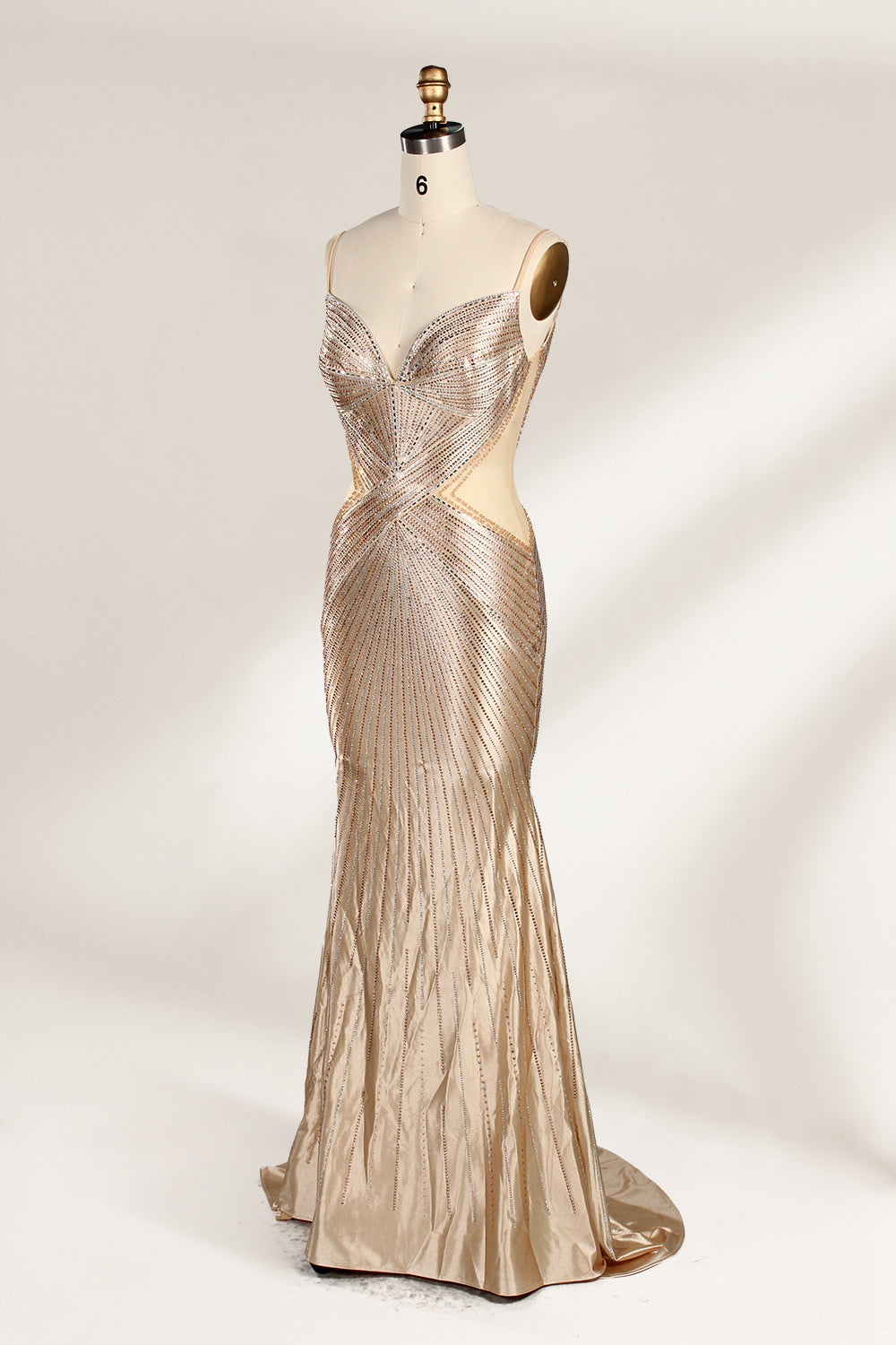 Set against a light backdrop, a mannequin presents a champagne - colored, beaded mermaid gown. It features a sweetheart neckline, cut - out sides, and intricate bead patterns radiating from the bodice. The shimmering beads and figure - hugging silhouette create a glamorous look, ideal for evening galas or proms.3