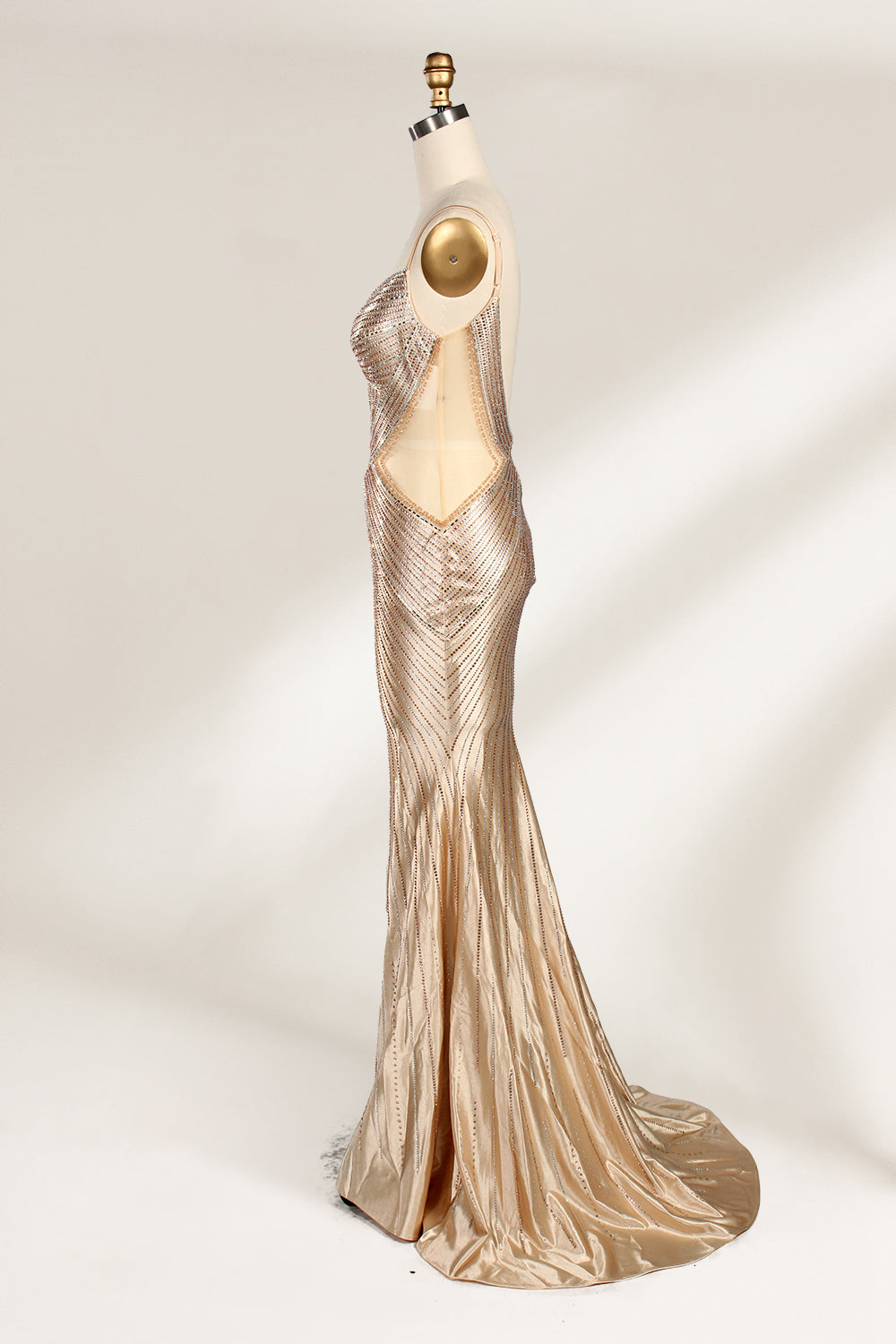 Set against a light backdrop, a mannequin presents a champagne - colored, beaded mermaid gown. It features a sweetheart neckline, cut - out sides, and intricate bead patterns radiating from the bodice. The shimmering beads and figure - hugging silhouette create a glamorous look, ideal for evening galas or proms.4