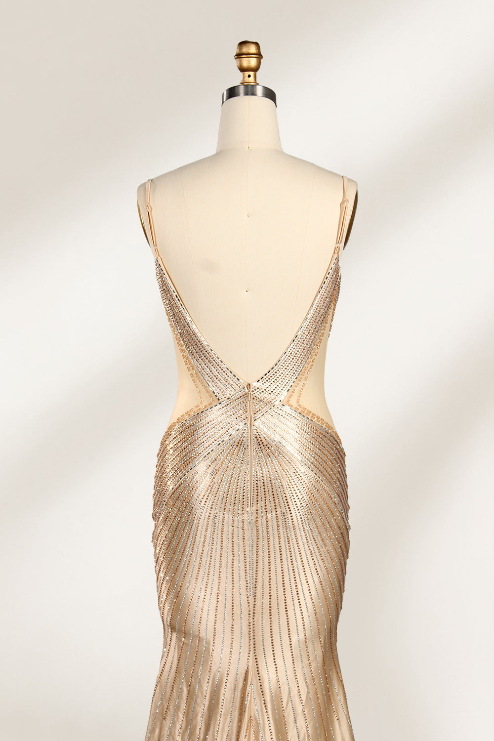 Set against a light backdrop, a mannequin presents a champagne - colored, beaded mermaid gown. It features a sweetheart neckline, cut - out sides, and intricate bead patterns radiating from the bodice. The shimmering beads and figure - hugging silhouette create a glamorous look, ideal for evening galas or proms.5