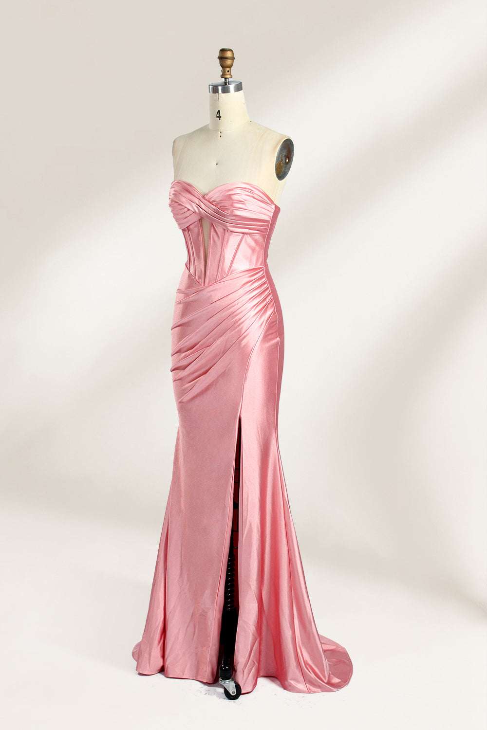 Against a gentle, light - colored backdrop, a mannequin showcases a strapless pink satin gown. The bust flaunts a twisted design, with a sheer insert at the bodice, and the waist is adorned with ruching. The mermaid - style skirt, featuring a high side slit, radiates elegance, perfect for formal galas.4