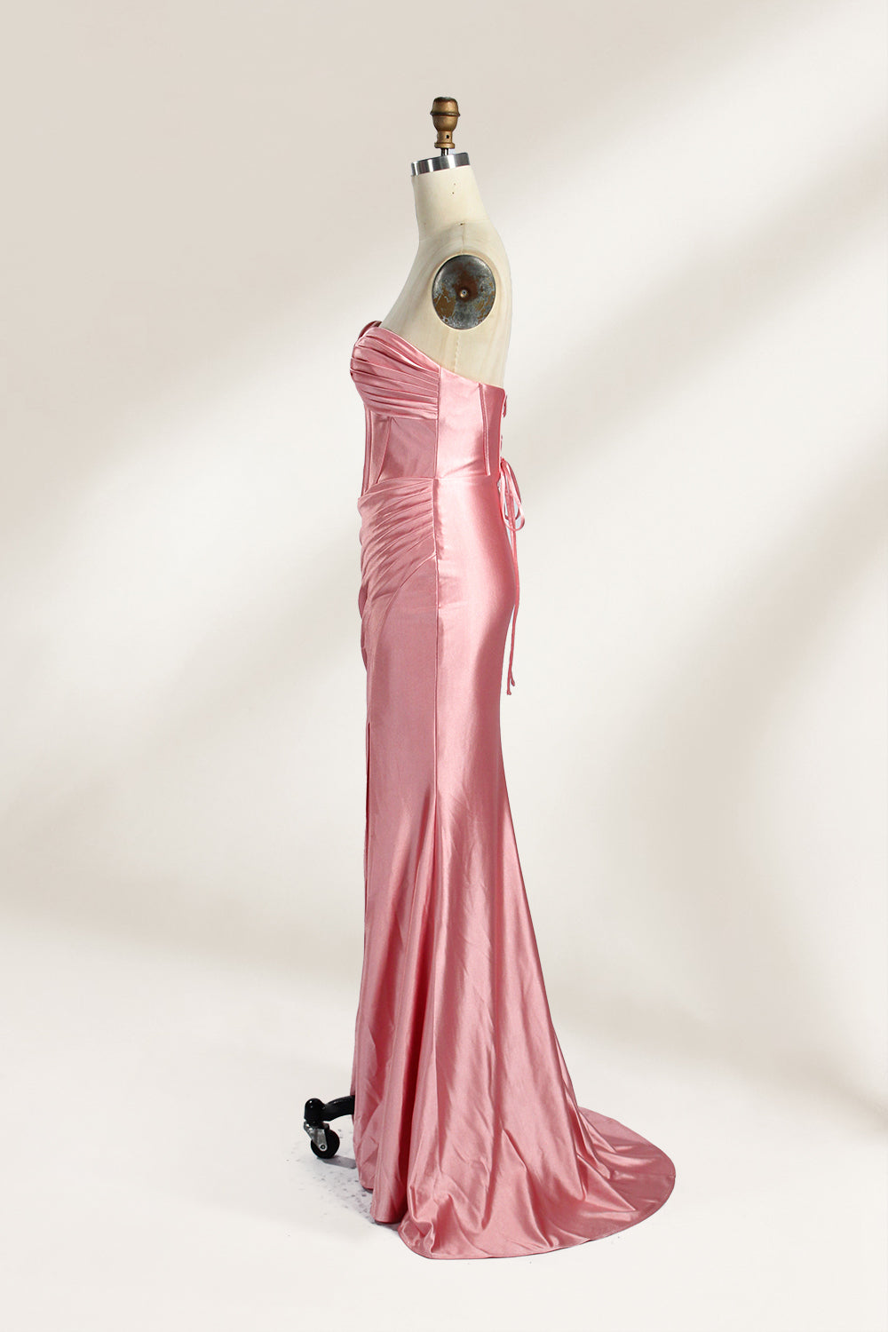 Against a gentle, light - colored backdrop, a mannequin showcases a strapless pink satin gown. The bust flaunts a twisted design, with a sheer insert at the bodice, and the waist is adorned with ruching. The mermaid - style skirt, featuring a high side slit, radiates elegance, perfect for formal galas.5