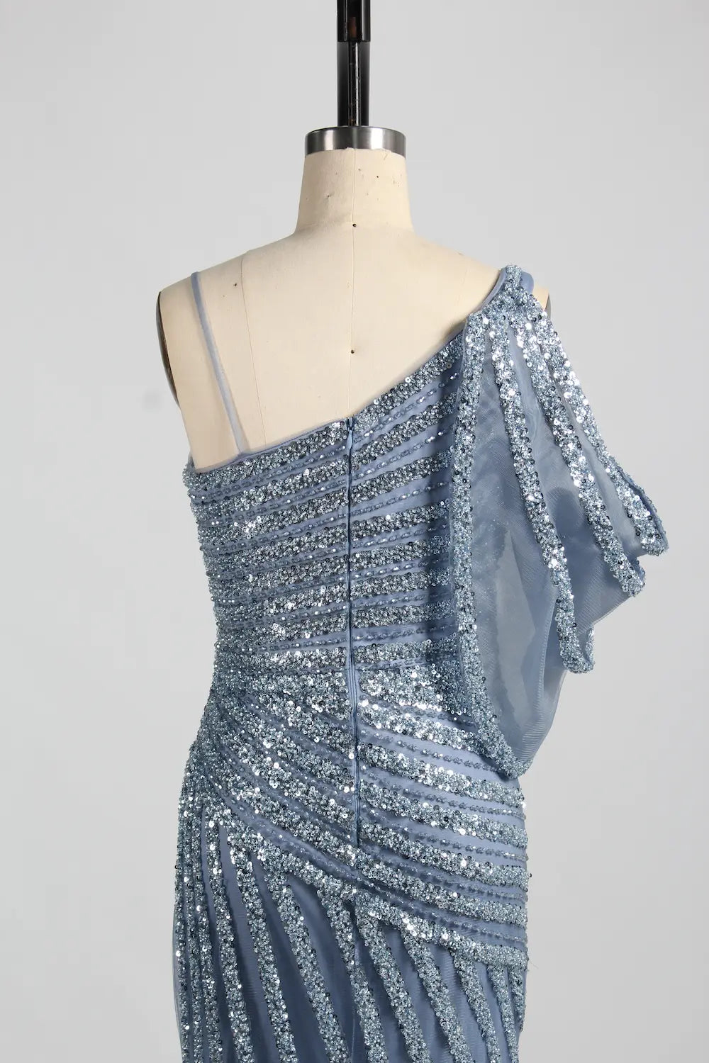 Blue one-shoulder beaded bodice with draped sleeve and vertical sparkle trim