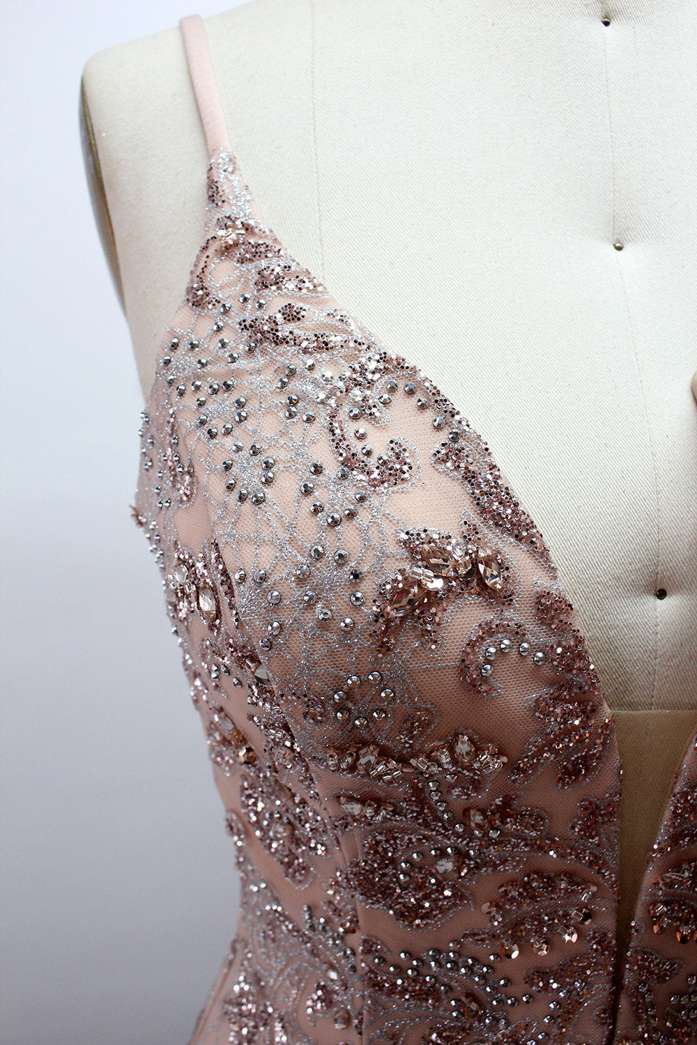 Presented on a mannequin is a blush - hued mermaid - cut gown. It features thin straps, a deep V - neckline, and is adorned with elaborate lace embroidery and sparkling accents. The sophisticated design exudes a glamorous and romantic charm, ideal for formal occasions such as proms or weddings.6