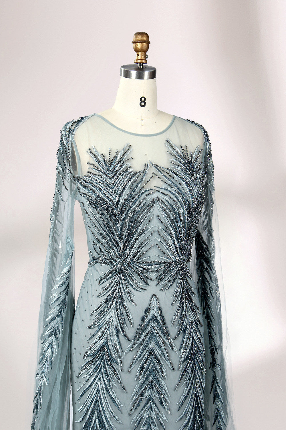 Showcased on a mannequin is a light - teal evening gown. It features a sheer high - neck design, long flowing sleeves, and intricate leaf - pattern embroidery. The gown's elegant and unique design exudes a sense of sophistication and grace, making it an ideal choice for formal events.
4