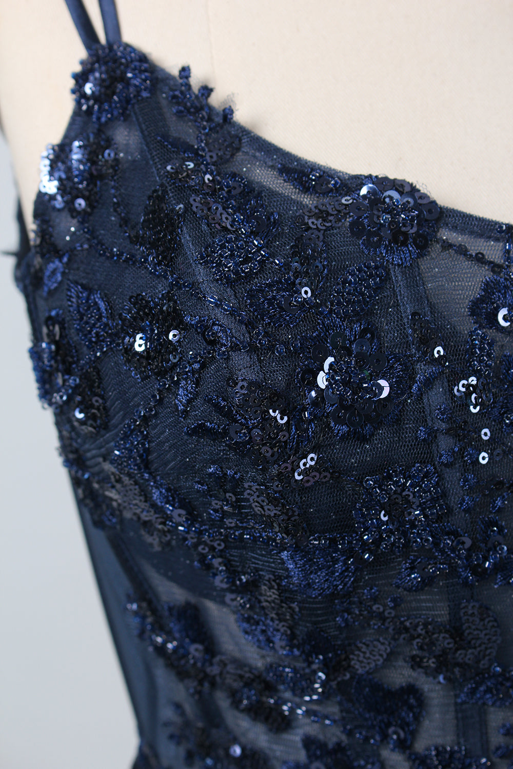 This is a floor - length evening dress in a deep navy hue. It has a strapless style with thin shoulder straps. The bodice is embellished with delicate beadwork and embroidery, creating an elegant and glamorous look. The skirt is form - fitting around the hips and flows down to the floor, featuring a side slit that adds allure and allows for easy movement. Displayed on a mannequin against a simple, light - colored backdrop, the dress exudes sophistication, perfect for special occasions like galas or proms.04