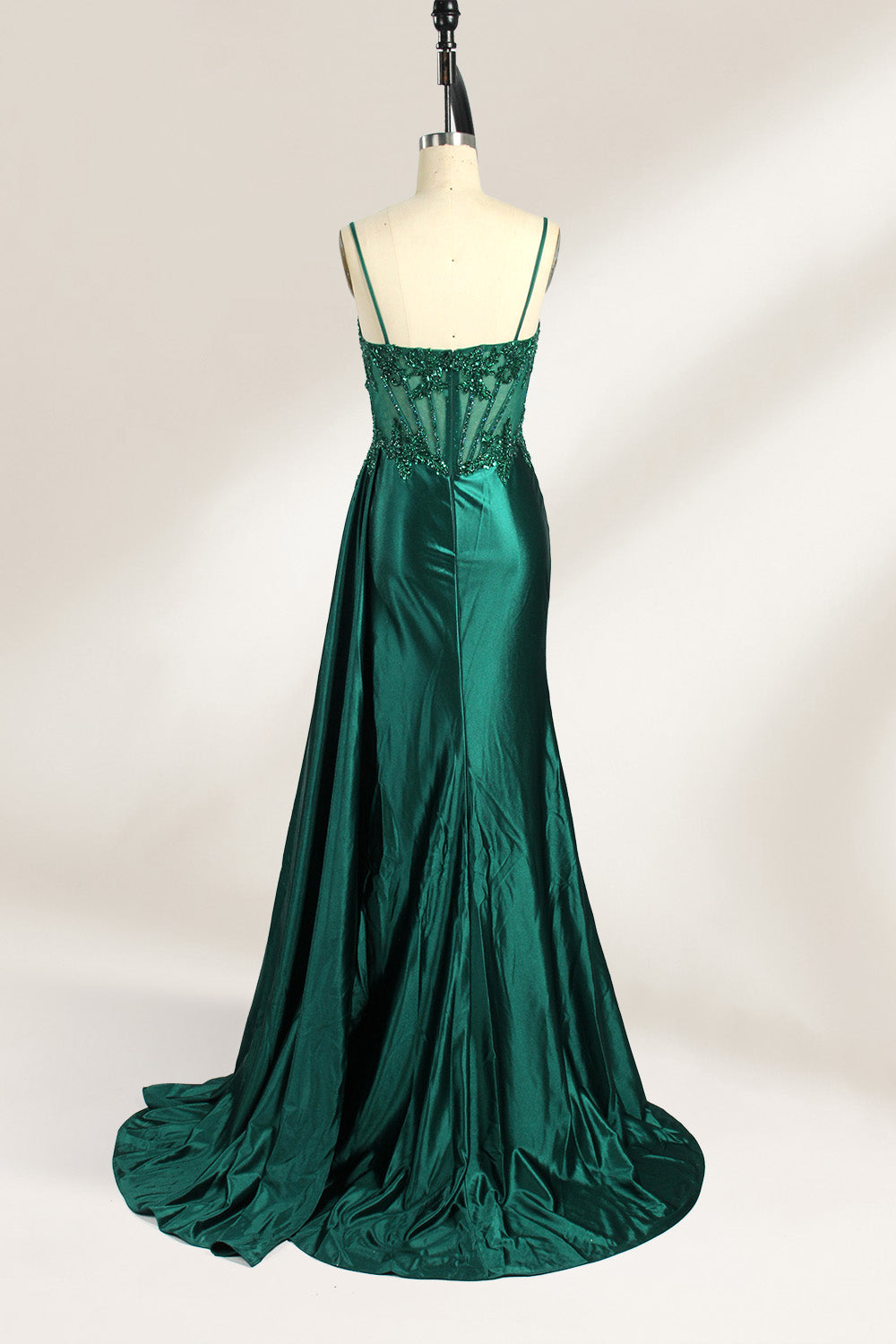 Photograph of an elegant, strapless green satin evening gown on a dress form. The dress features a fitted bodice adorned with intricate beading and lacework, transitioning into a flowing, ruched skirt that cascades to the floor. The gown's deep emerald green color exudes luxury and sophistication. The background is a plain, off-white studio setting, highlighting the dress's opulence. The dress form is positioned centrally, with the dress's front view prominently displayed.2