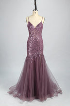 Photograph of a young Asian woman with fair skin and dark hair in a sleek bun, wearing a stunning, floor-length, deep blue evening gown. The gown has a plunging V-neckline, adorned with intricate beading and sequins, and features a sheer overlay with a high slit on one side, revealing a layer of tulle. The background is a soft, neutral gradient, highlighting the gown's elegance. She accessorizes with large, dangling earrings.7