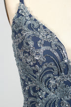 Photograph of a mannequin showcasing an elegant, floor-length evening gown. The gown features a deep V-neckline adorned with intricate blue floral embroidery, transitioning into a flowing, dark blue chiffon skirt. The mannequin stands against a plain, cream-colored backdrop. The dress exudes sophistication and luxury, perfect for formal events.06