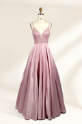 Photograph of a stylish, sleeveless, floor-length satin gown on a dress form. The dress features a deep V-neckline adorned with intricate lace, and a high-waisted bodice that flares into a voluminous skirt. The gown is a soft, blush pink color. The background is a plain, light beige, enhancing the dress's elegant design.01