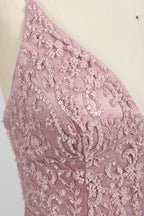 Photograph of a stylish, sleeveless, floor-length satin gown on a dress form. The dress features a deep V-neckline adorned with intricate lace, and a high-waisted bodice that flares into a voluminous skirt. The gown is a soft, blush pink color. The background is a plain, light beige, enhancing the dress's elegant design.04