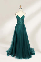 A mannequin showcases a dark - green tulle gown. It has thin spaghetti straps, a lace - detailed bodice, and a voluminous, flowing skirt. The elegant design, with its romantic tulle and delicate lace, suits formal events like galas or weddings.1