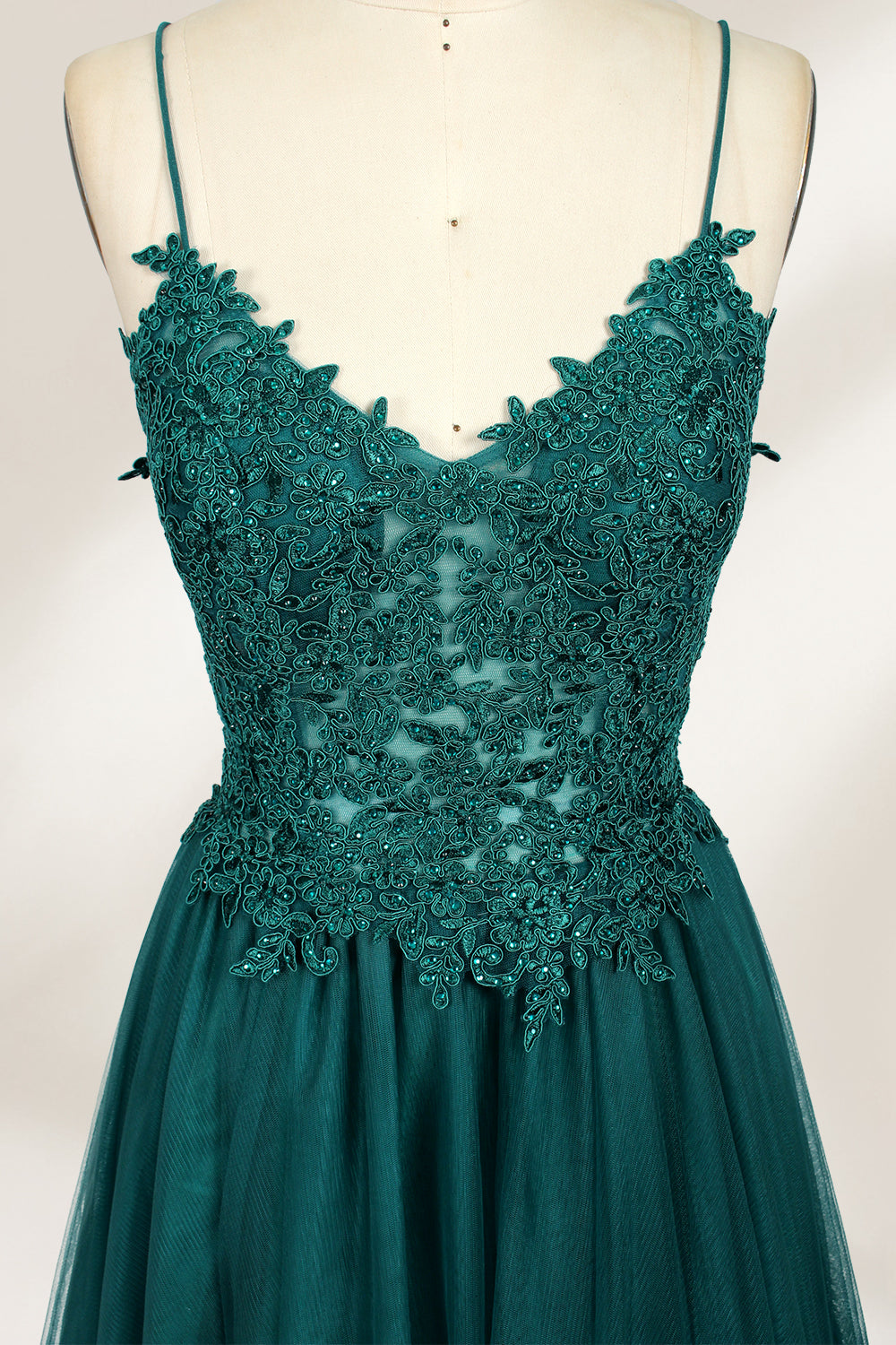 A mannequin showcases a dark - green tulle gown. It has thin spaghetti straps, a lace - detailed bodice, and a voluminous, flowing skirt. The elegant design, with its romantic tulle and delicate lace, suits formal events like galas or weddings.1
