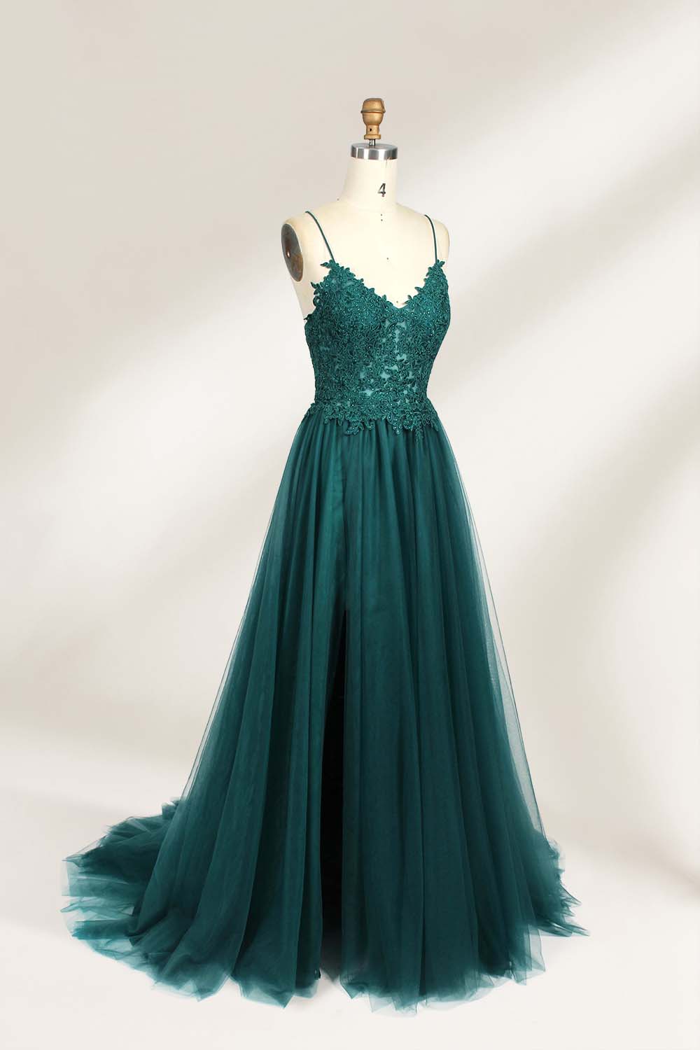 A mannequin showcases a dark - green tulle gown. It has thin spaghetti straps, a lace - detailed bodice, and a voluminous, flowing skirt. The elegant design, with its romantic tulle and delicate lace, suits formal events like galas or weddings.2