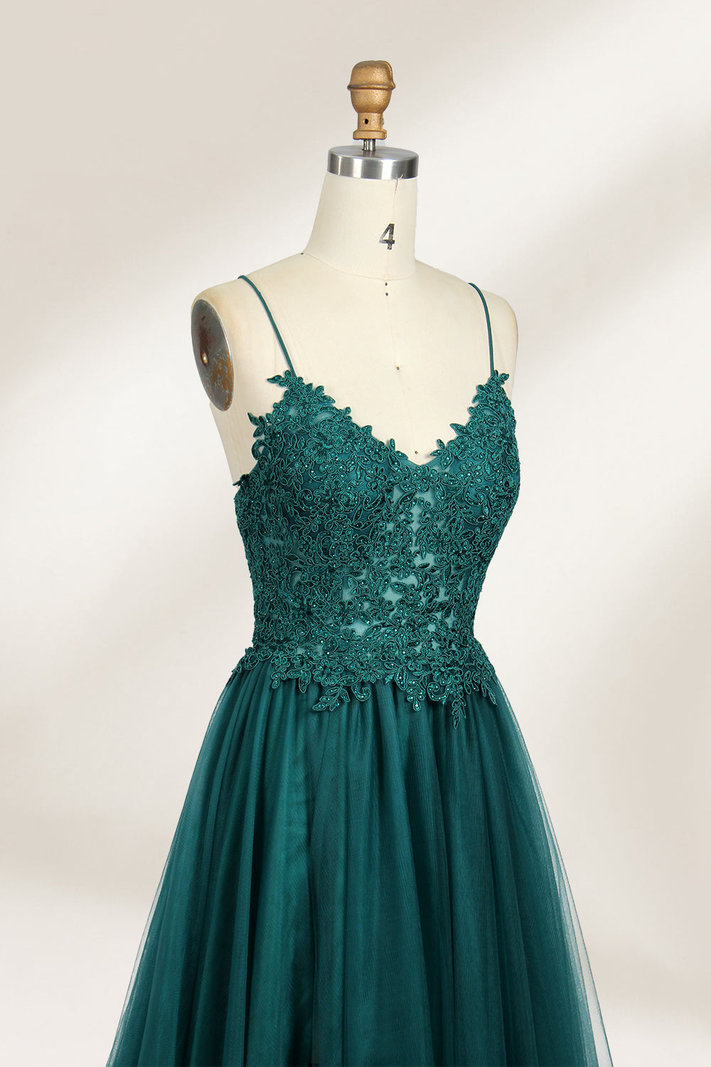 A mannequin showcases a dark - green tulle gown. It has thin spaghetti straps, a lace - detailed bodice, and a voluminous, flowing skirt. The elegant design, with its romantic tulle and delicate lace, suits formal events like galas or weddings.3