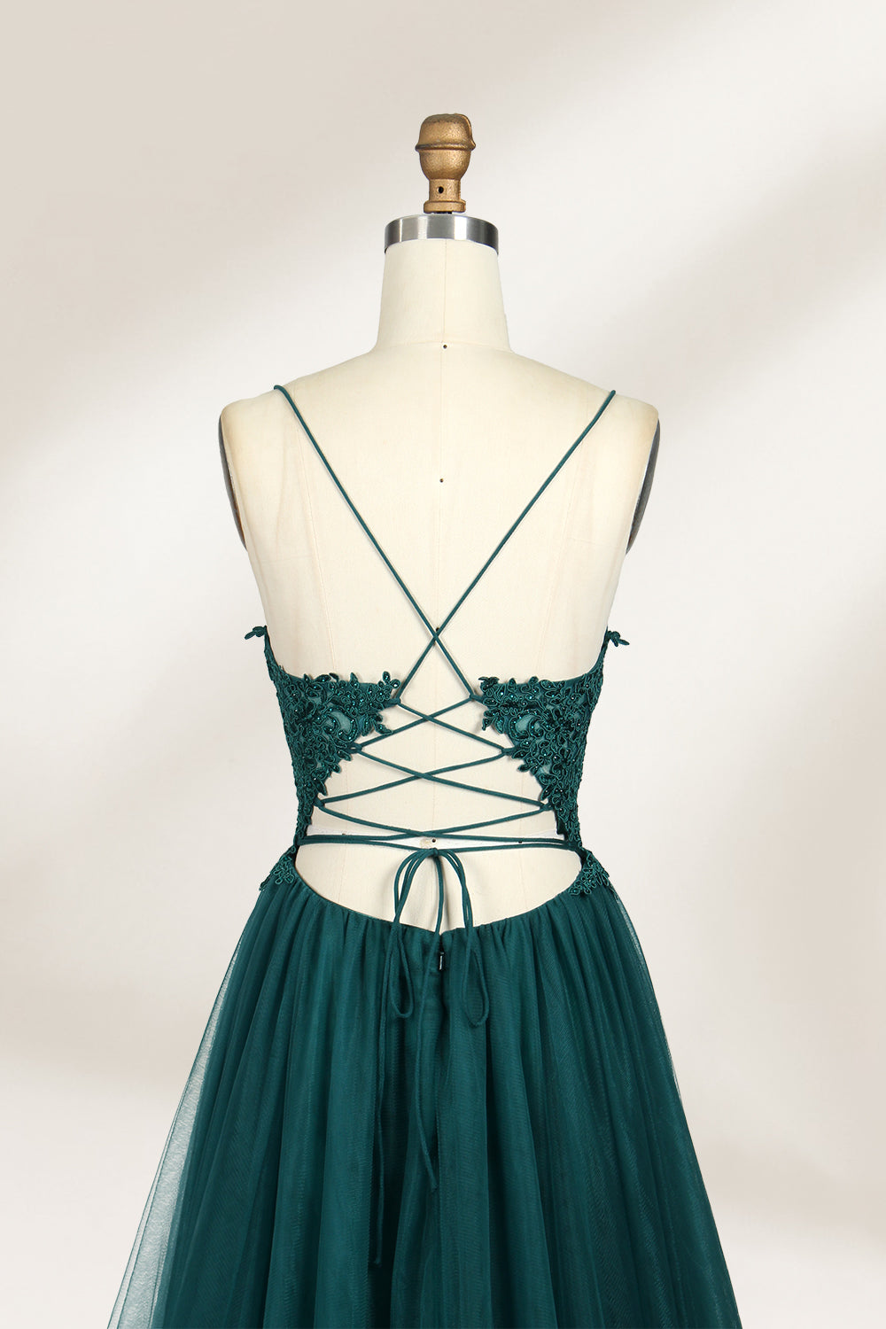 A mannequin showcases a dark - green tulle gown. It has thin spaghetti straps, a lace - detailed bodice, and a voluminous, flowing skirt. The elegant design, with its romantic tulle and delicate lace, suits formal events like galas or weddings.4