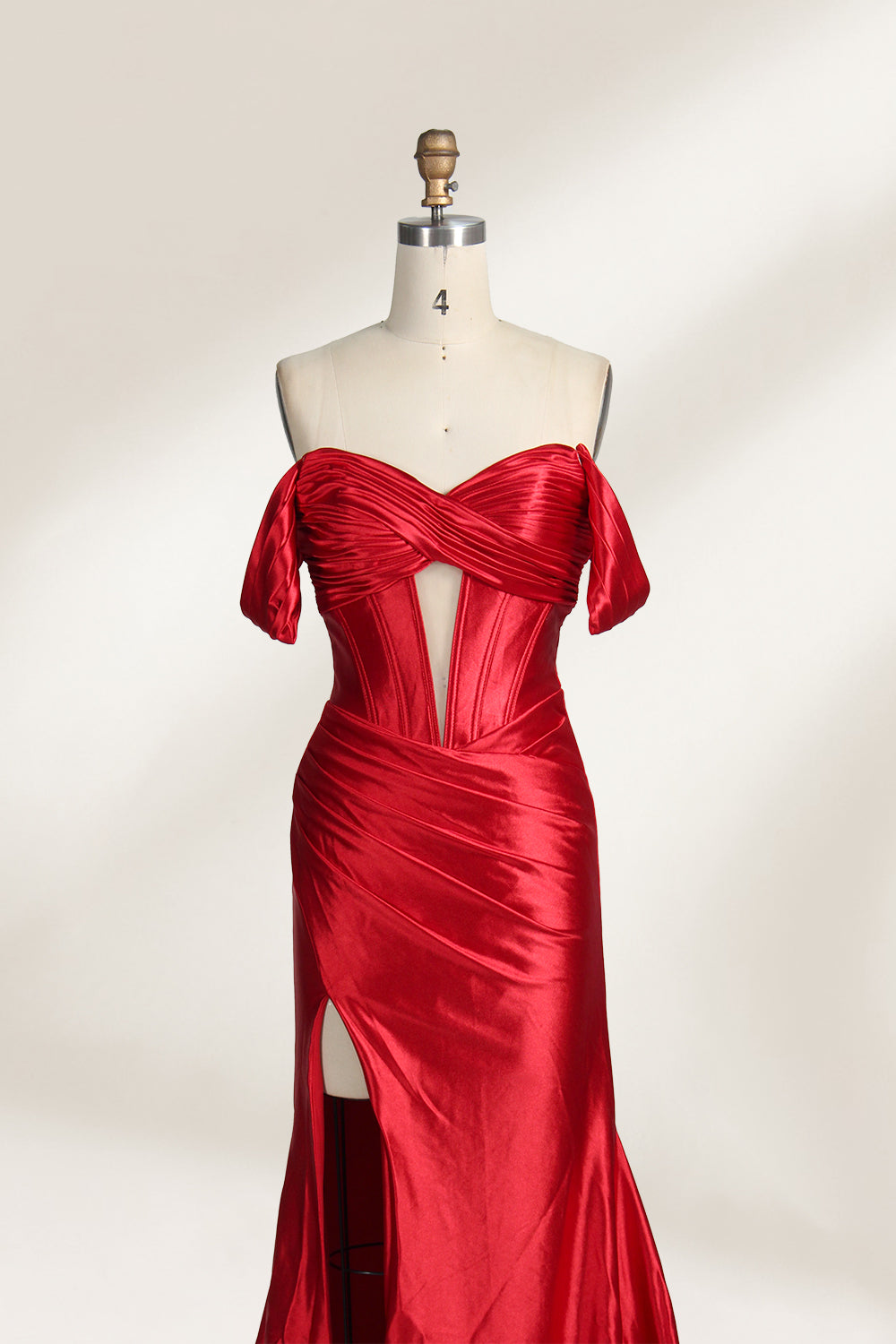  mannequin showcases a strapless red satin gown against a light - hued backdrop. It features an off - shoulder, twisted bodice with a sheer panel and a high side slit. The smooth satin fabric and elegant silhouette radiate sophistication, ideal for formal dinners or charity balls.3