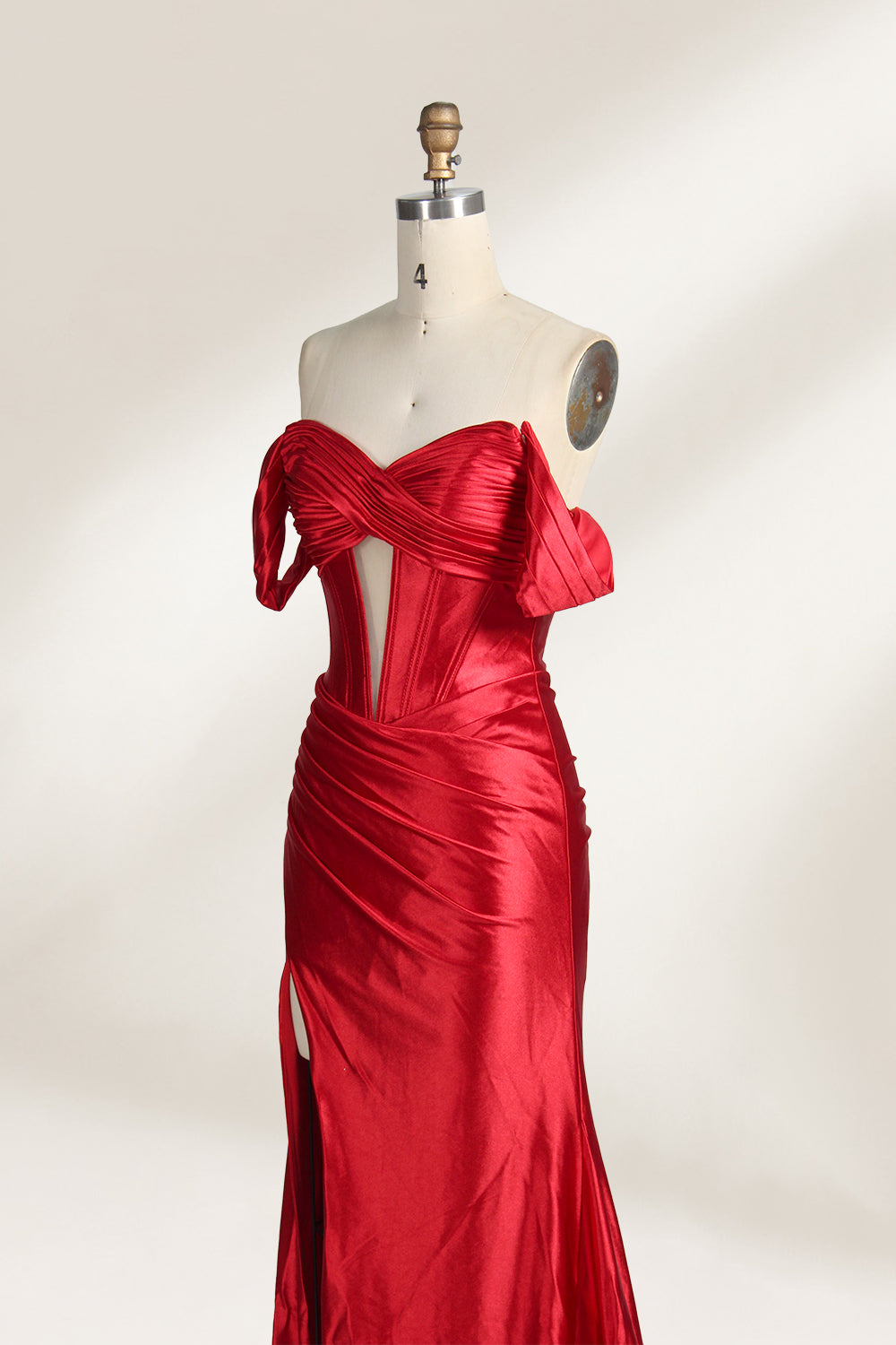  mannequin showcases a strapless red satin gown against a light - hued backdrop. It features an off - shoulder, twisted bodice with a sheer panel and a high side slit. The smooth satin fabric and elegant silhouette radiate sophistication, ideal for formal dinners or charity balls.4