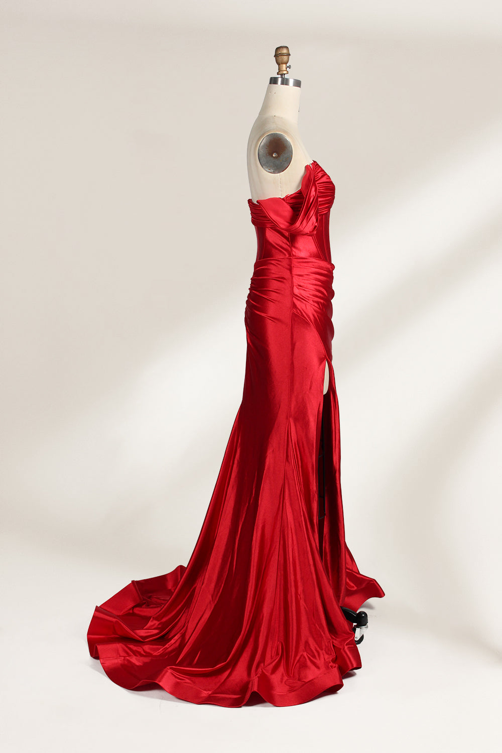  mannequin showcases a strapless red satin gown against a light - hued backdrop. It features an off - shoulder, twisted bodice with a sheer panel and a high side slit. The smooth satin fabric and elegant silhouette radiate sophistication, ideal for formal dinners or charity balls.