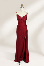 This is a burgundy satin evening gown displayed on a mannequin. It features a sweetheart neckline and thin shoulder straps. The dress has a ruched design along the bodice and waist, accentuating the figure, and a high side slit that adds an elegant, modern touch. The smooth satin fabric gives it a luxurious sheen, making it suitable for formal events like galas or weddings.01