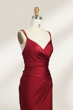 This is a burgundy satin evening gown displayed on a mannequin. It features a sweetheart neckline and thin shoulder straps. The dress has a ruched design along the bodice and waist, accentuating the figure, and a high side slit that adds an elegant, modern touch. The smooth satin fabric gives it a luxurious sheen, making it suitable for formal events like galas or weddings.04