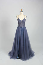 A mannequin showcases a dark - green tulle gown. It has thin spaghetti straps, a lace - detailed bodice, and a voluminous, flowing skirt. The elegant design, with its romantic tulle and delicate lace, suits formal events like galas or weddings.