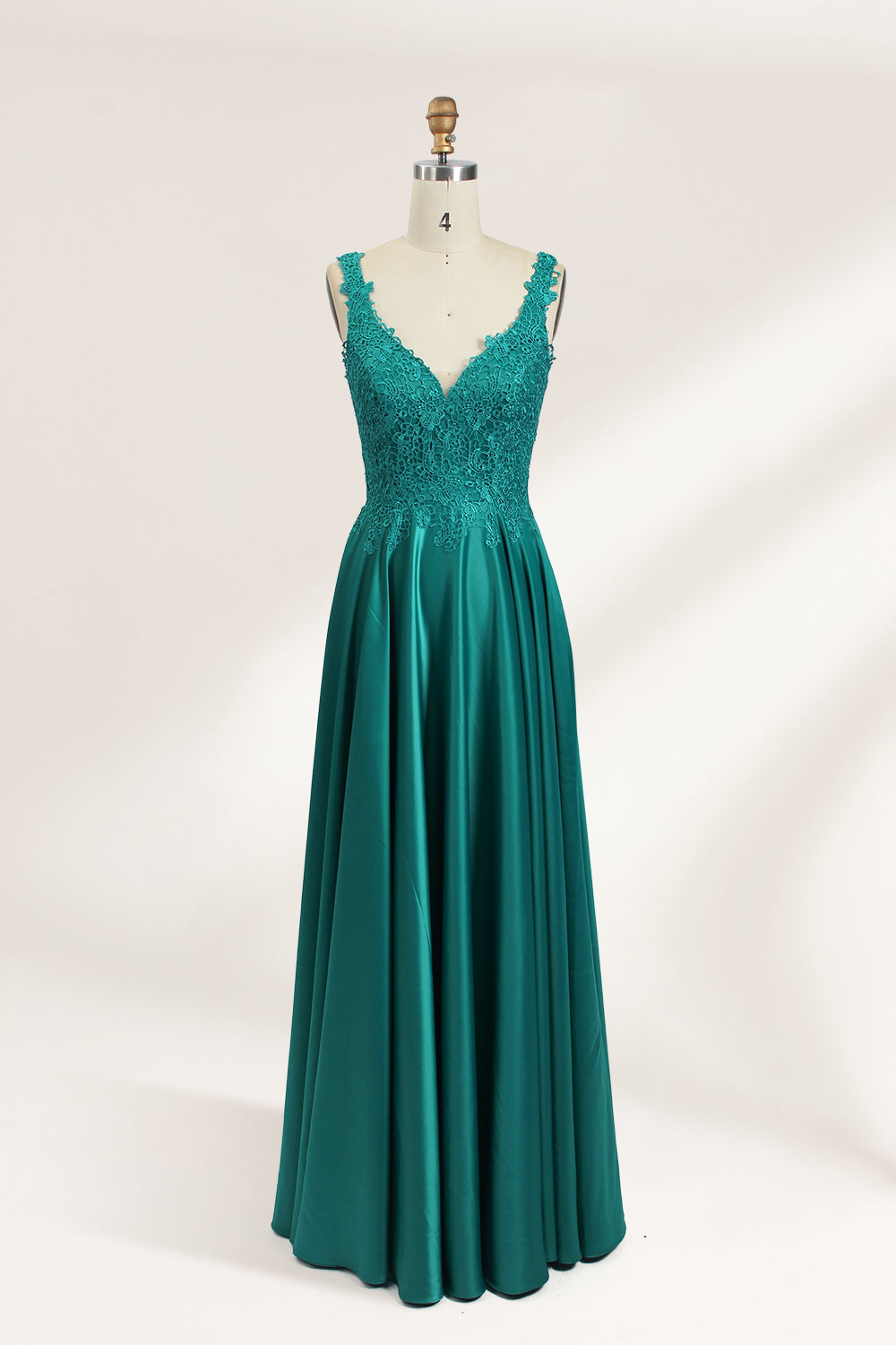 Photograph of a mannequin showcasing a teal, floor-length evening gown with a lace bodice and V-neckline. The gown features a fitted waist and a full, flowing skirt. The mannequin is set against a plain, light-colored background, highlighting the dress's elegant and luxurious design.01