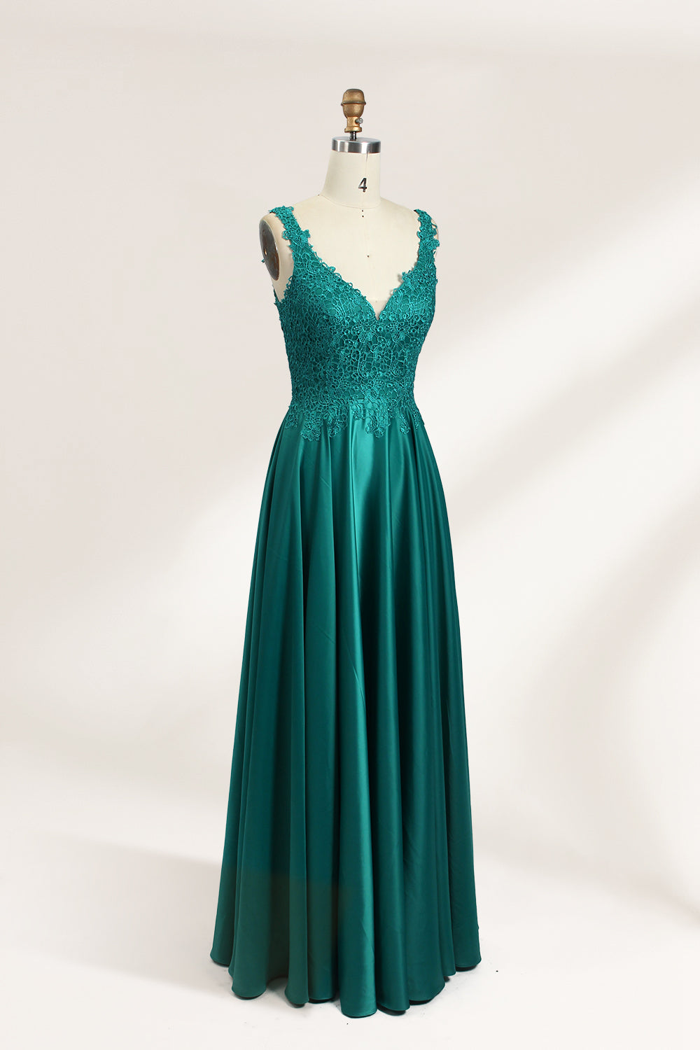 Photograph of a mannequin showcasing a teal, floor-length evening gown with a lace bodice and V-neckline. The gown features a fitted waist and a full, flowing skirt. The mannequin is set against a plain, light-colored background, highlighting the dress's elegant and luxurious design.04