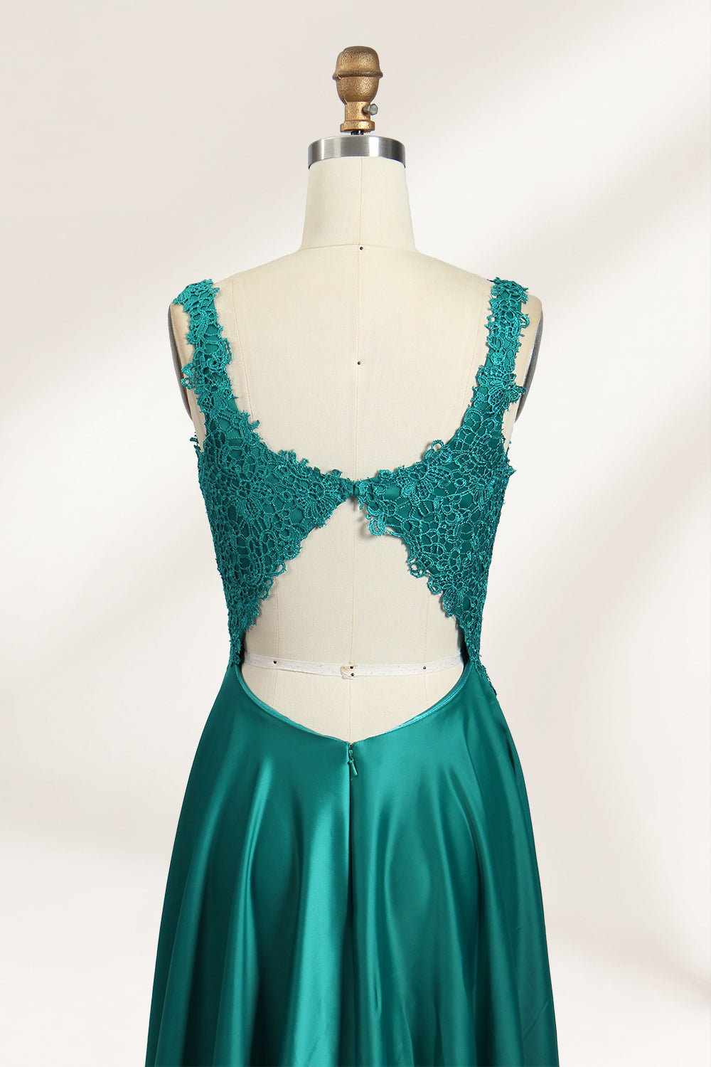 Photograph of a mannequin showcasing a teal, floor-length evening gown with a lace bodice and V-neckline. The gown features a fitted waist and a full, flowing skirt. The mannequin is set against a plain, light-colored background, highlighting the dress's elegant and luxurious design.06