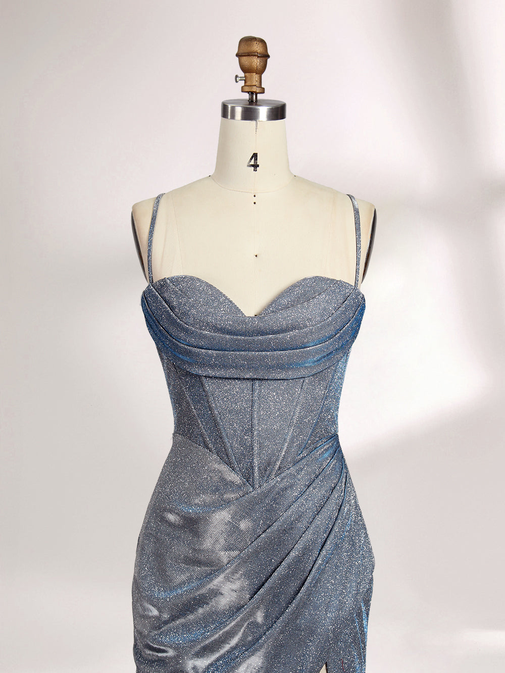 A woman stands against a light background, wearing a light - blue, shimmering gown. It has thin spaghetti straps, a cowl neckline, and a high side slit. The glittery fabric and elegant silhouette, paired with strappy heels, exude glamour, perfect for formal events like galas or proms.5