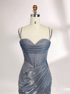 A woman stands against a light background, wearing a light - blue, shimmering gown. It has thin spaghetti straps, a cowl neckline, and a high side slit. The glittery fabric and elegant silhouette, paired with strappy heels, exude glamour, perfect for formal events like galas or proms.5