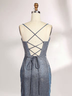 A woman stands against a light background, wearing a light - blue, shimmering gown. It has thin spaghetti straps, a cowl neckline, and a high side slit. The glittery fabric and elegant silhouette, paired with strappy heels, exude glamour, perfect for formal events like galas or proms.