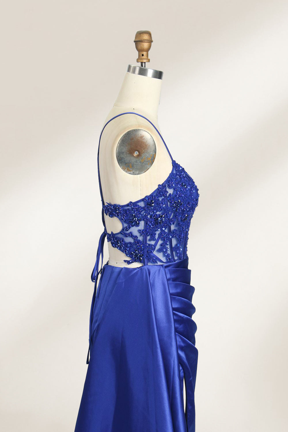 A mannequin showcases a royal - blue gown with thin straps. The bodice features intricate bead embroidery and sheer panels, while the skirt has a ruched design and a high side slit. The satin fabric and elegant details make it perfect for formal events like proms or galas, exuding sophistication.6