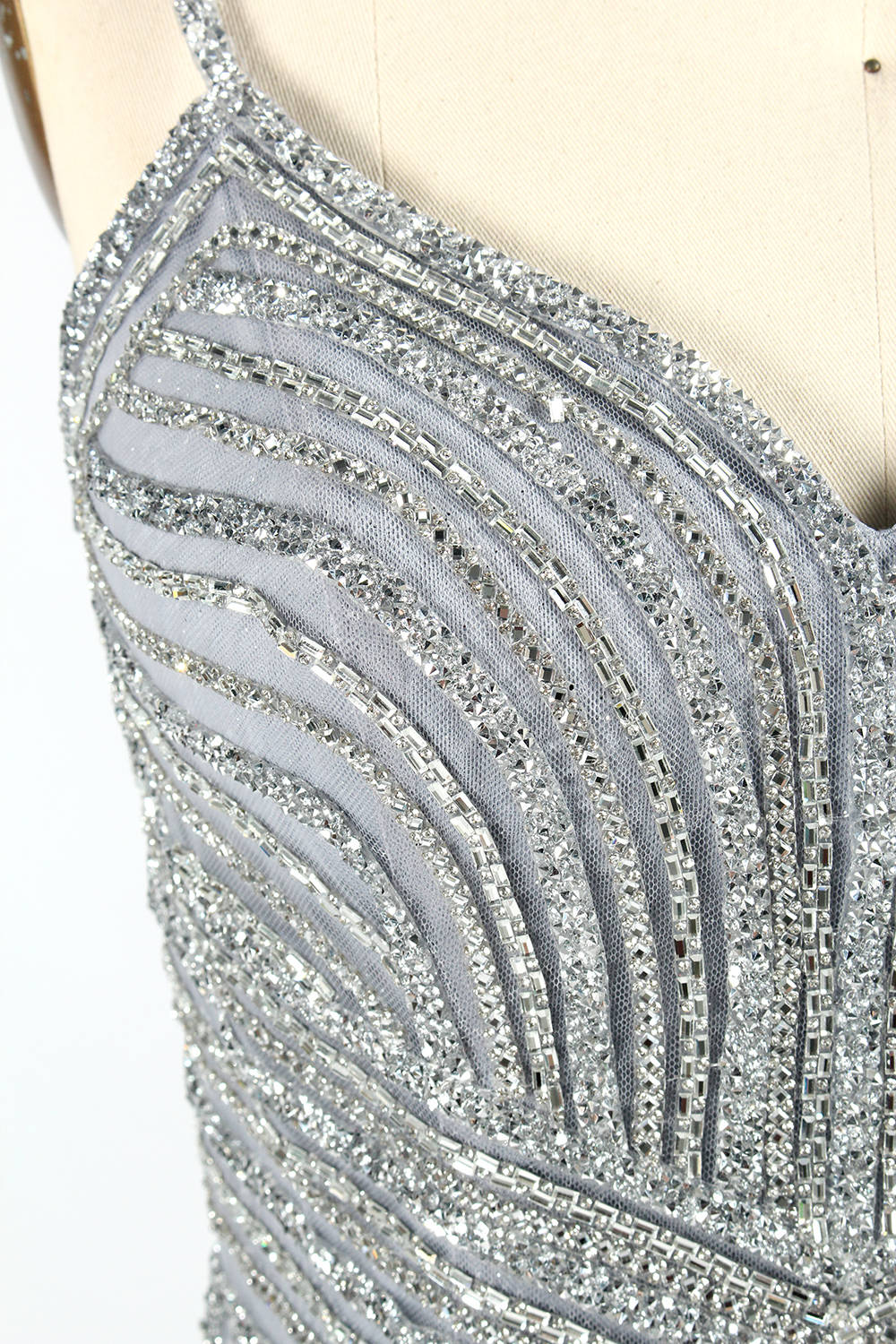 Set against a light background, a mannequin presents a grey tulle gown. It has thin straps, a sweetheart neckline, and a mermaid - shaped skirt. The detailed silver bead embroidery creates an elegant pattern, making it ideal for formal events like proms, radiating sophistication.