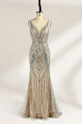 Against a light - hued backdrop, a mannequin displays a nude - toned tulle gown featuring silver beaded embellishments. It has thin straps, a deep V - neckline, and a mermaid - shaped skirt. The detailed beadwork weaves sophistication, perfect for formal dinners or weddings, where the beaded elegance complements the occasion.1