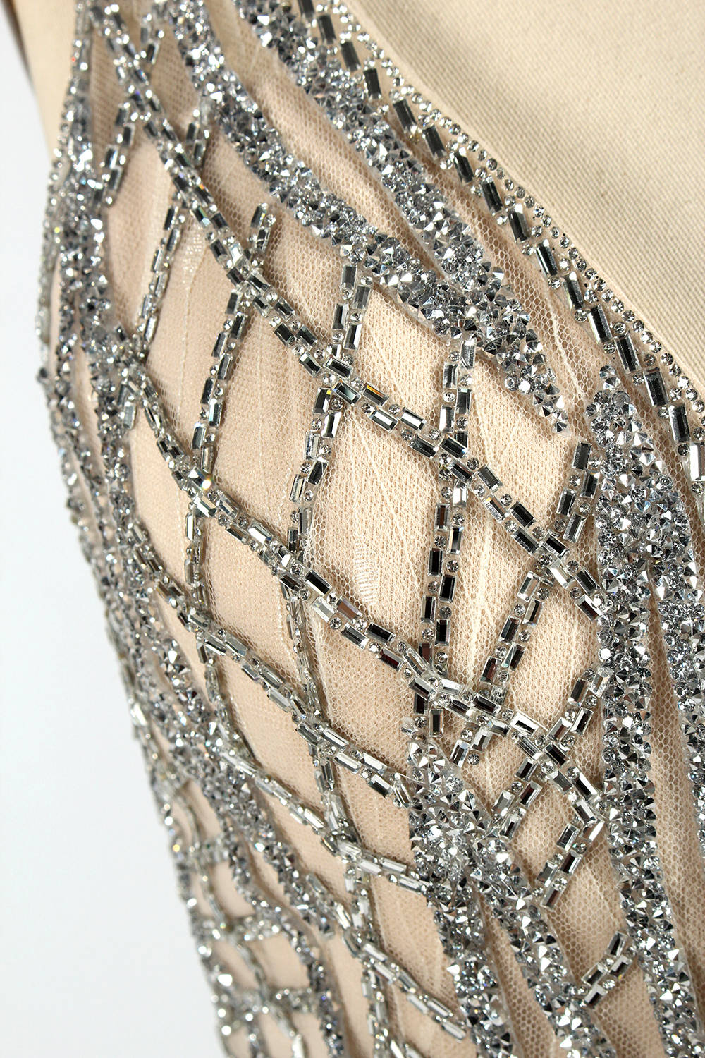 Against a light - hued backdrop, a mannequin displays a nude - toned tulle gown featuring silver beaded embellishments. It has thin straps, a deep V - neckline, and a mermaid - shaped skirt. The detailed beadwork weaves sophistication, perfect for formal dinners or weddings, where the beaded elegance complements the occasion.7