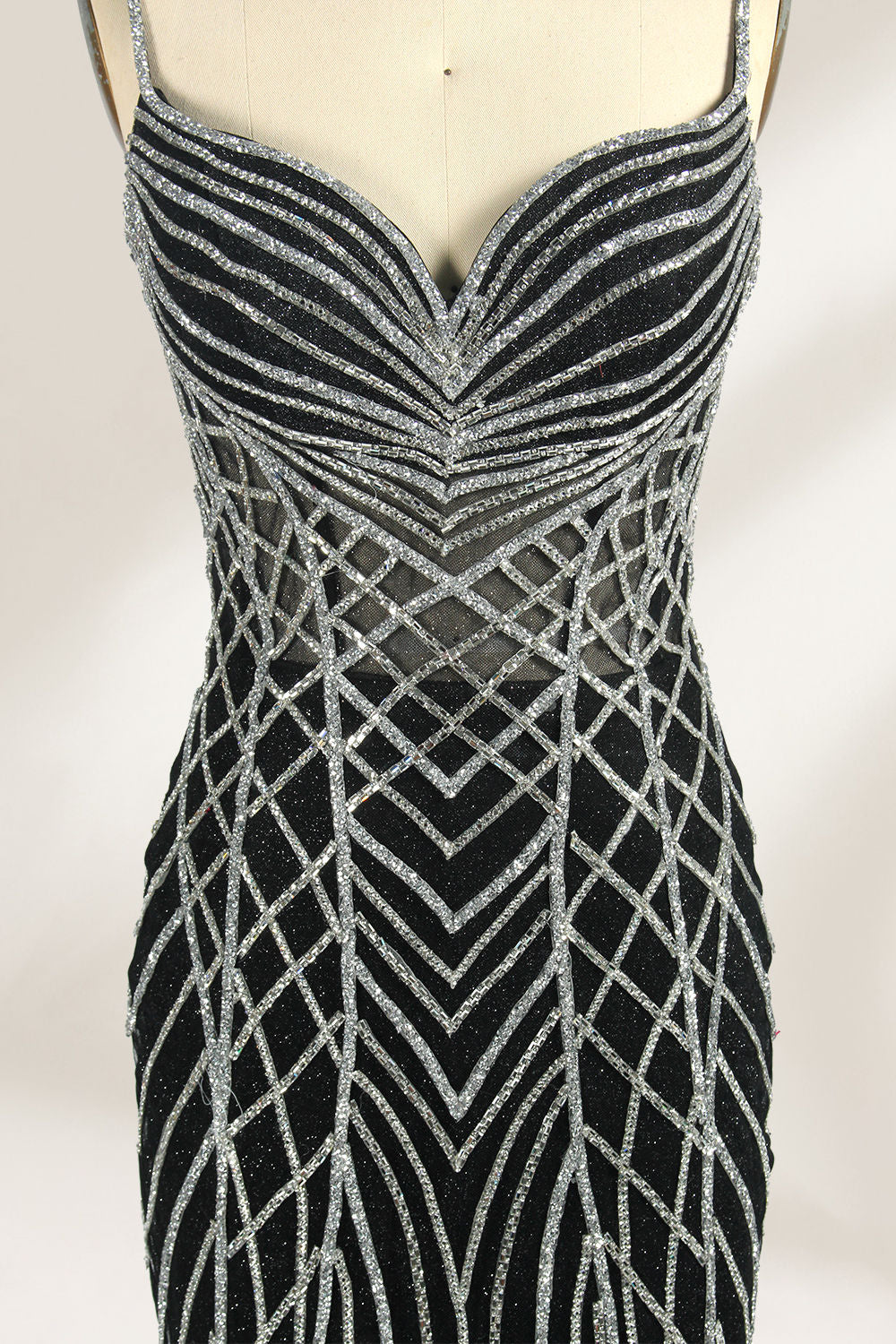Set against a light background, a mannequin presents a black tulle gown with silver - toned beaded embellishments. Thin straps, a sweetheart neckline, and a mermaid - style skirt complete the look. The geometric bead patterns add a touch of glamour, ideal for proms or formal events where the beaded artistry stands out.5
