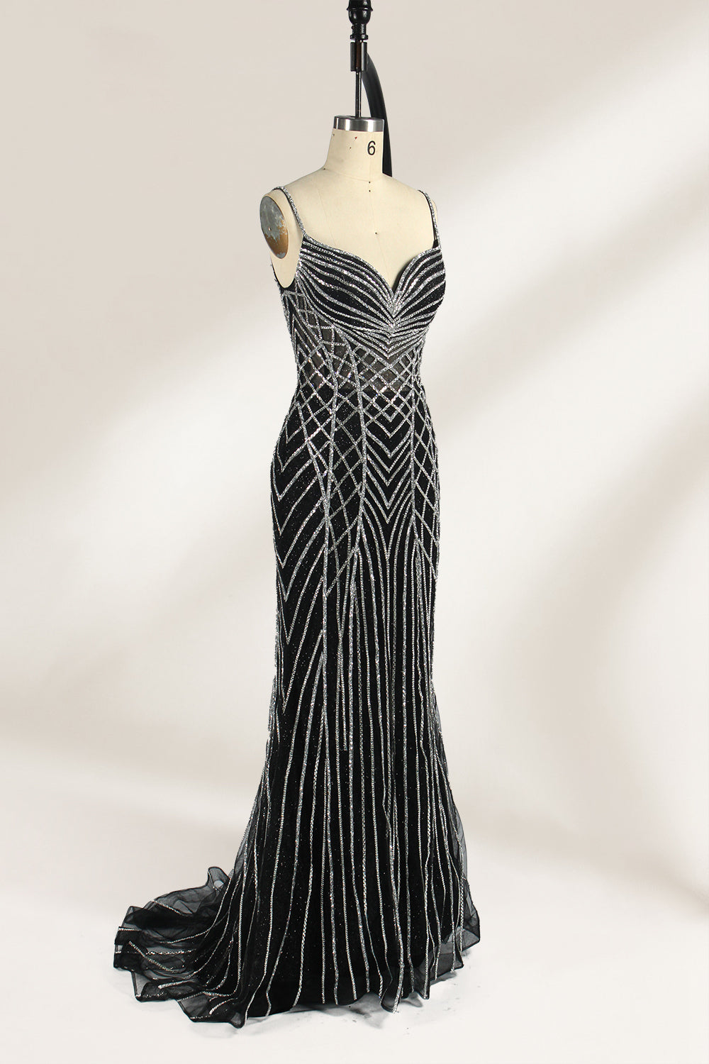 Set against a light background, a mannequin presents a black tulle gown with silver - toned beaded embellishments. Thin straps, a sweetheart neckline, and a mermaid - style skirt complete the look. The geometric bead patterns add a touch of glamour, ideal for proms or formal events where the beaded artistry stands out.2