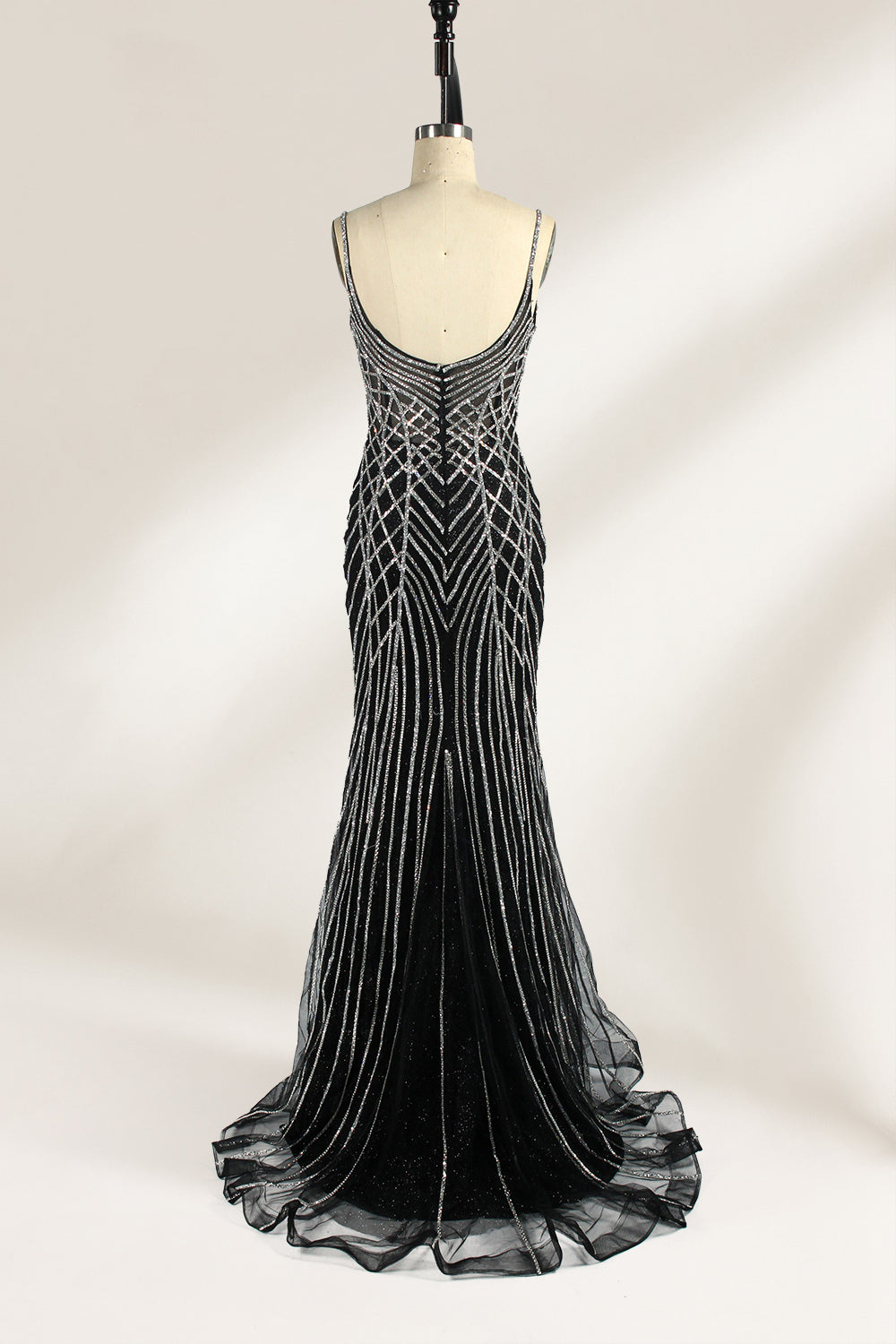 Set against a light background, a mannequin presents a black tulle gown with silver - toned beaded embellishments. Thin straps, a sweetheart neckline, and a mermaid - style skirt complete the look. The geometric bead patterns add a touch of glamour, ideal for proms or formal events where the beaded artistry stands out.4