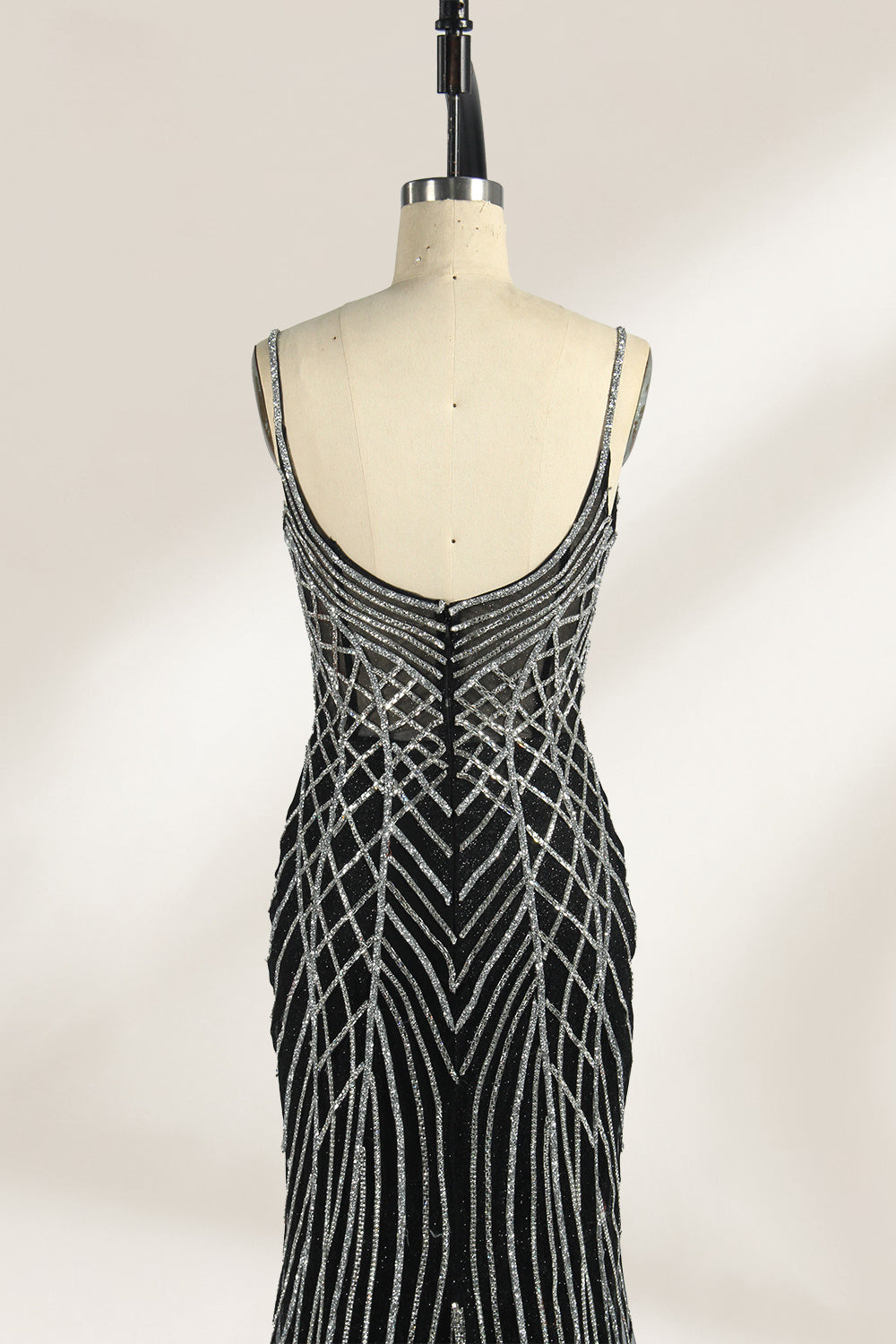 Set against a light background, a mannequin presents a black tulle gown with silver - toned beaded embellishments. Thin straps, a sweetheart neckline, and a mermaid - style skirt complete the look. The geometric bead patterns add a touch of glamour, ideal for proms or formal events where the beaded artistry stands out.3