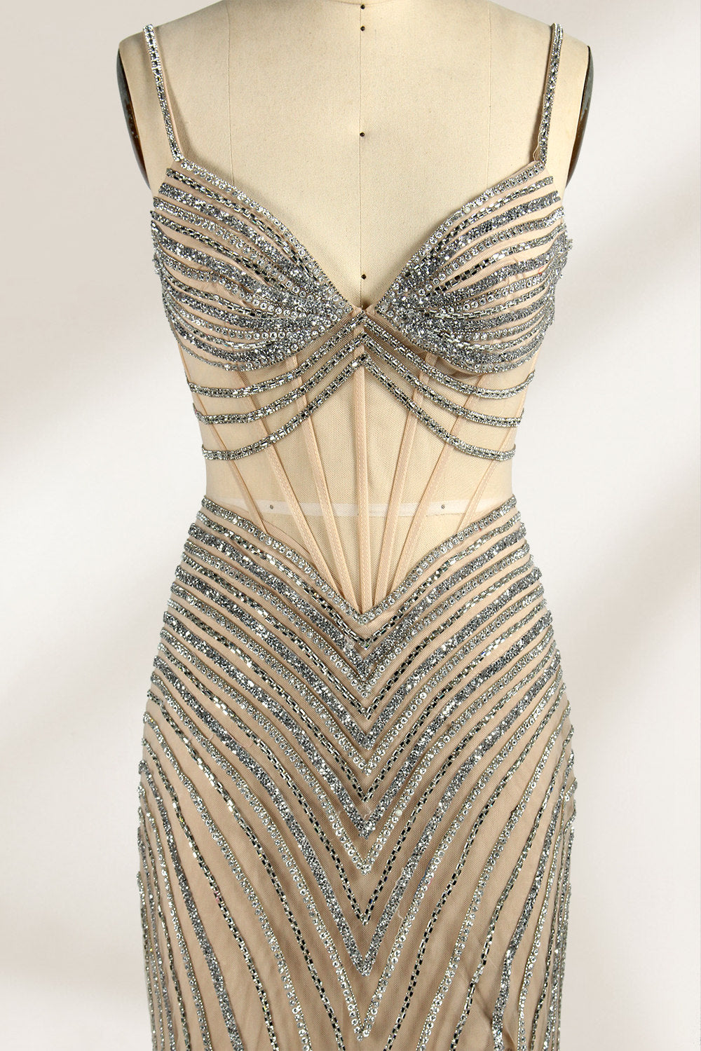 A mannequin numbered “6” displays a black tulle gown against a light backdrop. It features thin straps, a deep V - neckline, and a mermaid silhouette. The intricate silver bead patterns, sheer bodice with vertical accents, and high side slit add glamour, perfect for formal galas.6