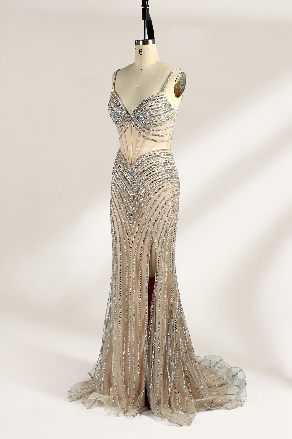 A mannequin numbered “6” displays a black tulle gown against a light backdrop. It features thin straps, a deep V - neckline, and a mermaid silhouette. The intricate silver bead patterns, sheer bodice with vertical accents, and high side slit add glamour, perfect for formal galas.5