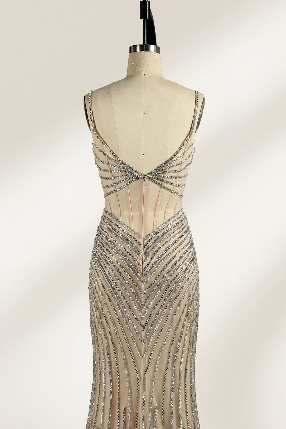 A mannequin numbered “6” displays a black tulle gown against a light backdrop. It features thin straps, a deep V - neckline, and a mermaid silhouette. The intricate silver bead patterns, sheer bodice with vertical accents, and high side slit add glamour, perfect for formal galas.3