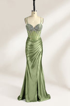A mannequin presents a green satin gown with a bejeweled, sheer bodice against a light backdrop. It features thin straps, a sweetheart neckline, and a mermaid - shaped skirt. The sparkling embellishments and smooth fabric exude elegance, perfect for formal galas.1