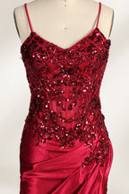 Photograph of a mannequin wearing a stunning, floor-length, navy blue satin evening gown. The gown features a deep V-back with thin straps and intricate sequin detailing along the back and neckline. The fitted bodice gradually flares into a flowing, elegant train. The mannequin stands against a plain, light beige backdrop, highlighting the gown's luxurious texture and shimmering finish. The gown exudes sophistication and glamour, ideal for formal events.3
