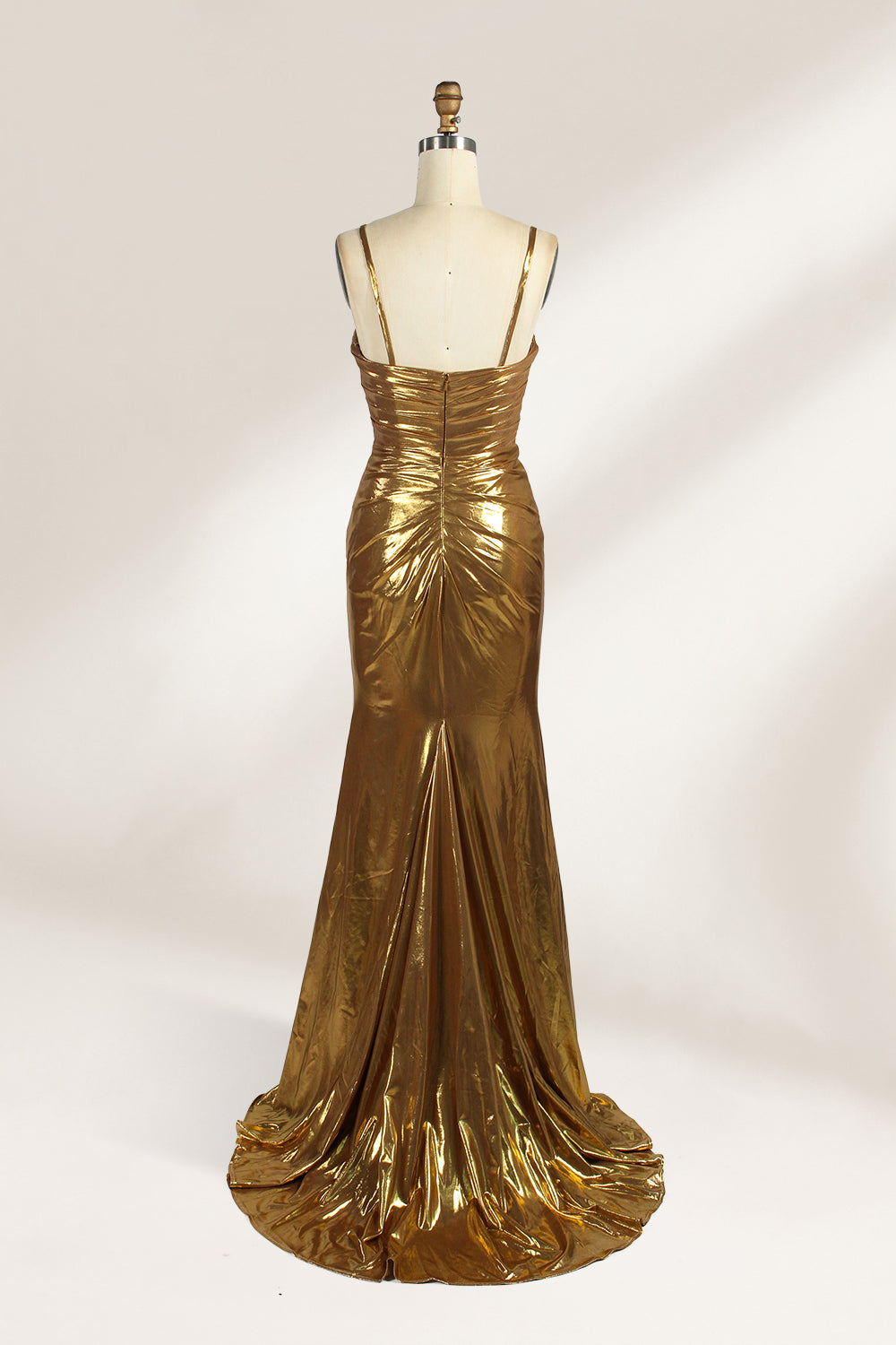 A golden strapless evening gown is displayed on a mannequin. The bodice is adorned with intricate beadwork, and the skirt, made of a shiny metallic fabric, features a high side slit and a small train, creating a glamorous and elegant look, perfect for formal events.2